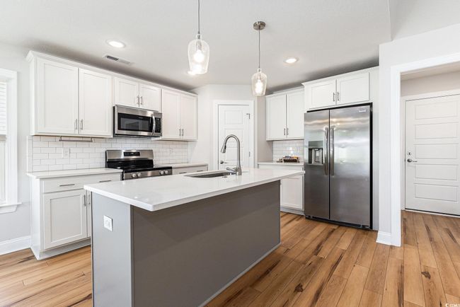 Kitchen with stainless steel appliances, light countertops, white cabinets, and recessed lighting | Image 12