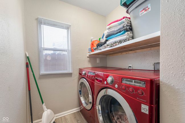 clothes washing area featuring laundry area, wood finished floors, washing machine and clothes dryer, and baseboards | Image 17