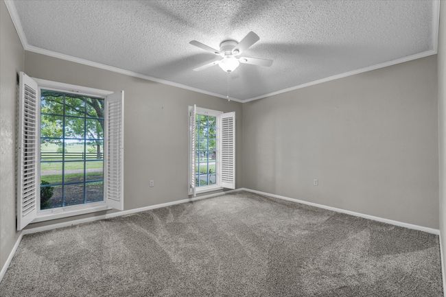 Unfurnished room with a ceiling fan, a textured ceiling, carpet floors, and ornamental molding | Image 14