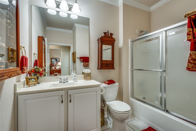 Bathroom featuring crown molding, vanity, enclosed tub / shower combo, and tile patterned flooring | Image 16
