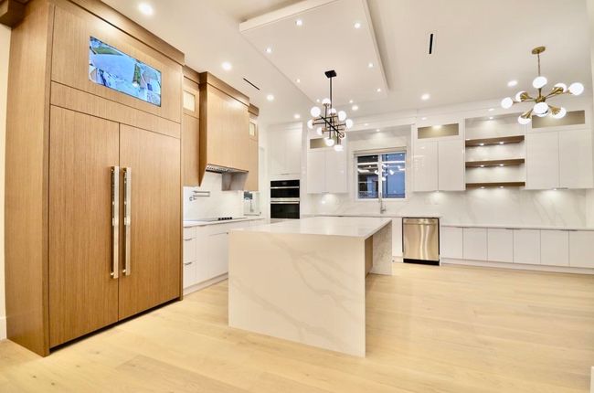 Kitchen featuring modern cabinets, a chandelier, paneled fridge, dishwasher, and recessed lighting | Image 6
