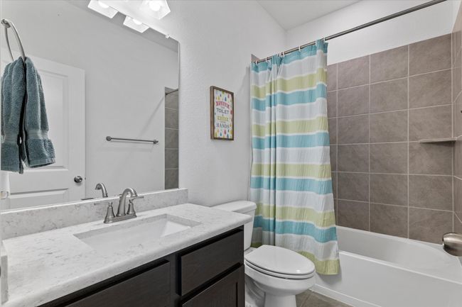 Bathroom with tile patterned floors, shower / bath combo with shower curtain, vanity, and toilet | Image 31