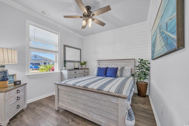 Bedroom featuring wood finished floors, baseboards, ornamental molding, ceiling fan, and wooden walls | Image 7