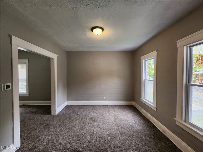 Carpeted empty room with a healthy amount of sunlight and a textured ceiling | Image 5