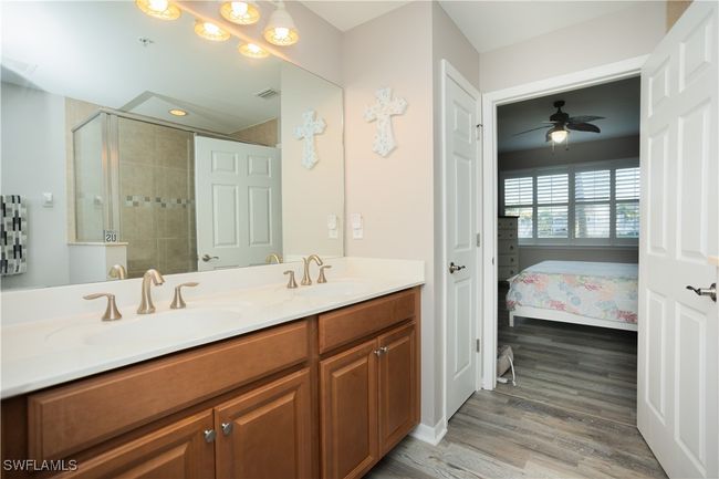 Ensuite bathroom featuring a tile shower, double vanity, vinyl finished floors, and a sink | Image 14