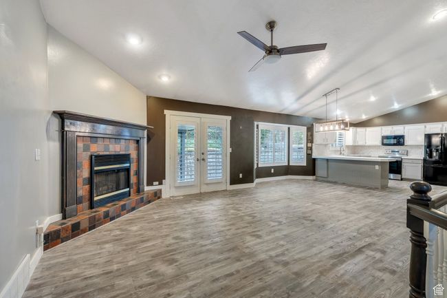 Living room with vaulted ceiling, visible vents, french doors, light wood-type flooring, and ceiling fan | Image 4