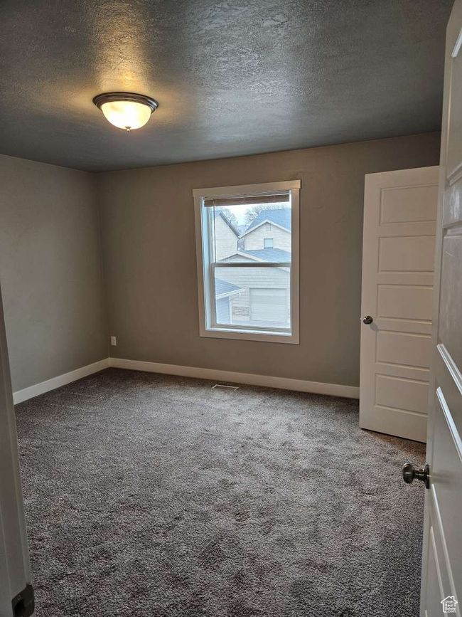 Carpeted empty room featuring a textured ceiling, baseboards, and visible vents | Image 14