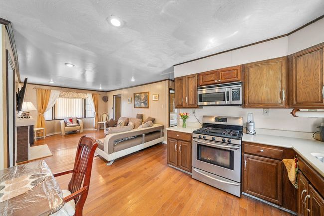 Kitchen featuring stainless steel appliances, light countertops, open floor plan, light wood-type flooring, and recessed lighting | Image 9