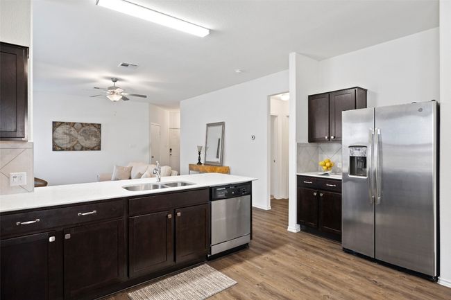 Kitchen featuring stainless steel appliances, tasteful backsplash, dark brown cabinets, light countertops, and wood finished floors | Image 13