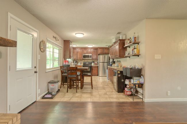Kitchen featuring stainless steel appliances, a textured ceiling, a peninsula, open shelves, and backsplash | Image 13