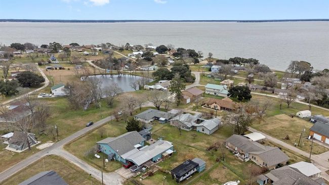 This aerial photo shows a peaceful lakeside neighborhood with open green spaces, and tree-lined streets. The lake provides scenic views, adding to the suburban charm. | Image 38