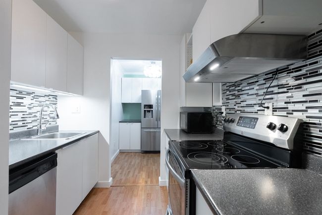Kitchen featuring stainless steel appliances, extractor fan, white cabinets, backsplash, and a sink | Image 10