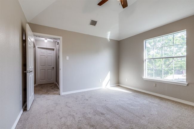 Carpeted empty room featuring baseboards, a ceiling fan, visible vents, and vaulted ceiling | Image 19
