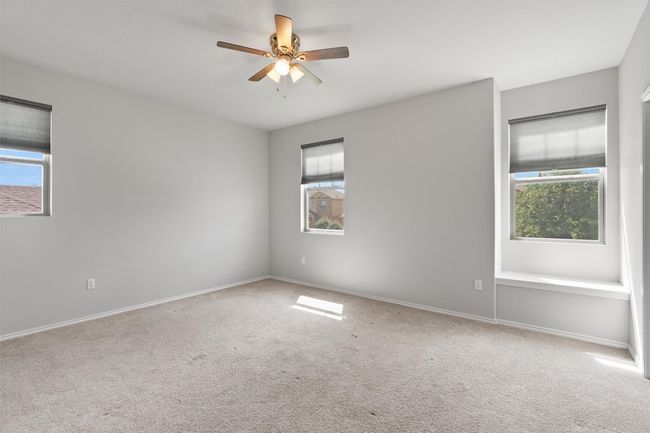 Another nice-sized bedroom with a ceiling fan, several windows, a window seat, and a walk-in closet. | Image 25