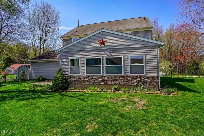 Rear view of house with a yard, stone siding, and fence | Image 44