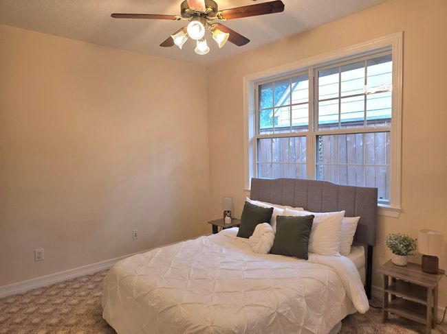 Cozy bedroom with neutral walls, ceiling fan, and carpeted floor. | Image 25
