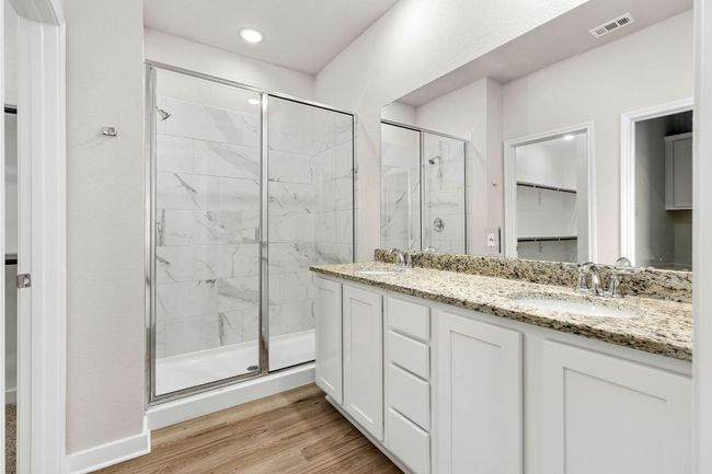 Full bathroom featuring wood finished floors, a sink, visible vents, double vanity, and a stall shower | Image 23