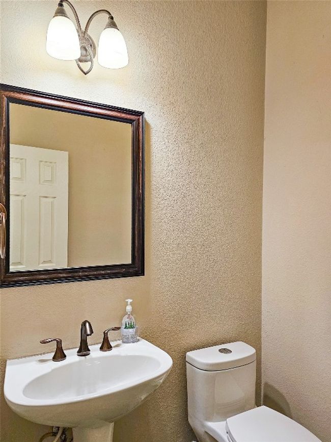 Bathroom featuring toilet, a sink, and a textured wall | Image 15