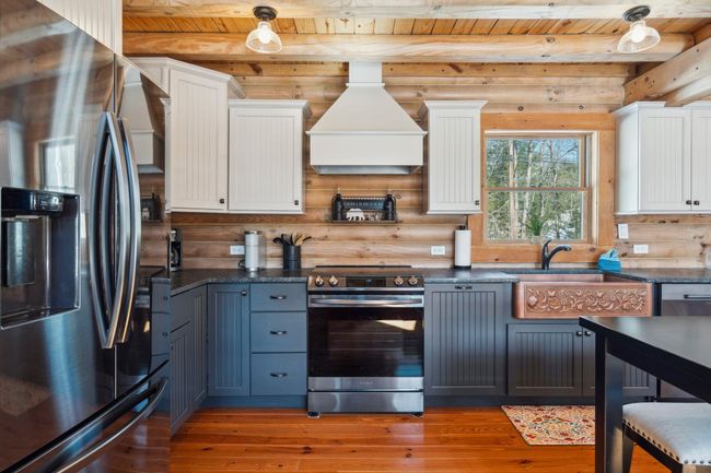 With leathered granite, copper sink, two-toned cabinets, black stainless steel appliances and hardwood floors | Image 8