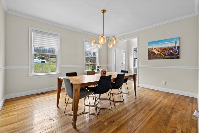 Dining room featuring light wood finished floors, a notable chandelier, visible vents, and crown molding | Image 4