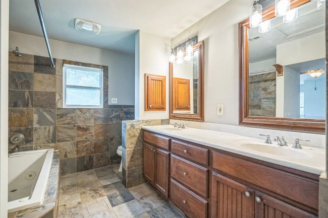 Full bathroom featuring double vanity, a jetted tub, tile walls, and a shower | Image 9