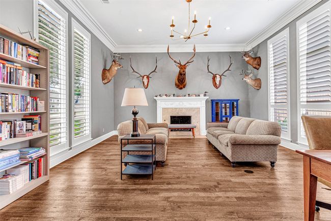 Wow! The formal living room is awash with light from windows on two sides, one highlighting views of the park, the other showcasing the pool and patio. An expansive room makes entertaining fun, with a gas log fireplace ready to keep things warm once the cooler weather arrives. | Image 8
