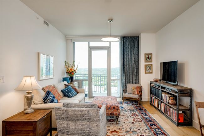 Living area with expansive windows and light wood-style floors | Image 7