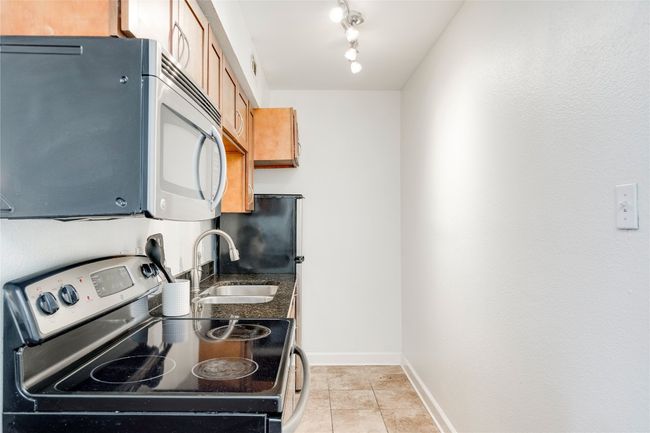 Kitchen featuring appliances with stainless steel finishes, a sink, light tile patterned floors, baseboards, and rail lighting | Image 14