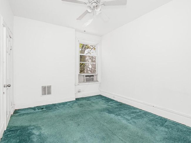 Carpeted empty room featuring visible vents, a ceiling fan, and cooling unit | Image 11