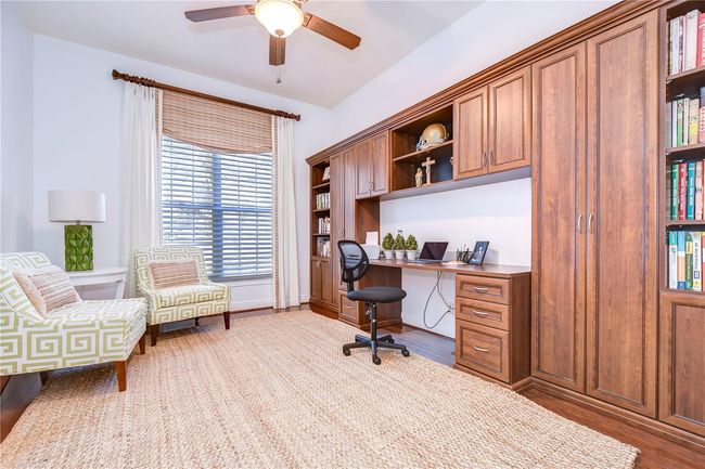This bright and inviting space features custom wooden cabinetry and a sleek work desk, offering both style and function. | Image 8