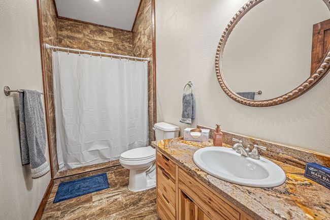 Full bath with toilet, vanity, stone finish floor, and a shower with shower curtain | Image 23