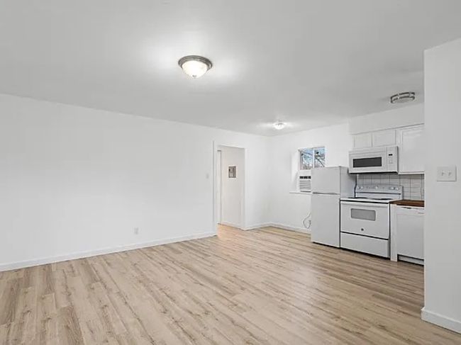 Kitchen featuring white appliances, light wood-style floors, white cabinetry, and tasteful backsplash | Image 15
