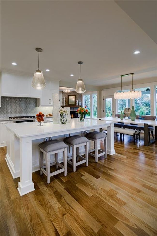 Kitchen with a kitchen island, white cabinets, light hardwood / wood-style floors, backsplash, and decorative light fixtures | Image 14