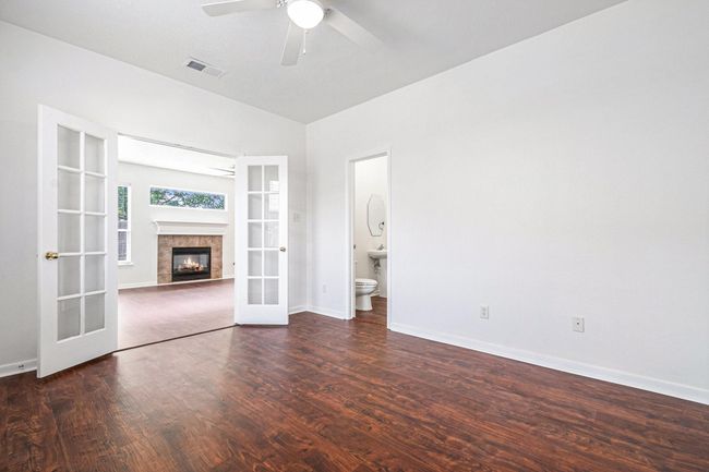 This photo showcases the offices, featuring French doors leading to a living area with a fireplace. There's a ceiling fan and an adjacent bathroom, adding convenience and style. | Image 4