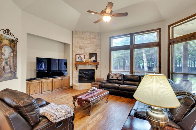 Living area with ceiling fan, light wood-style floors, a fireplace, and lofted ceiling | Image 18
