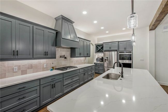 Kitchen with custom range hood, gray cabinetry, a sink, and appliances with stainless steel finishes | Image 9