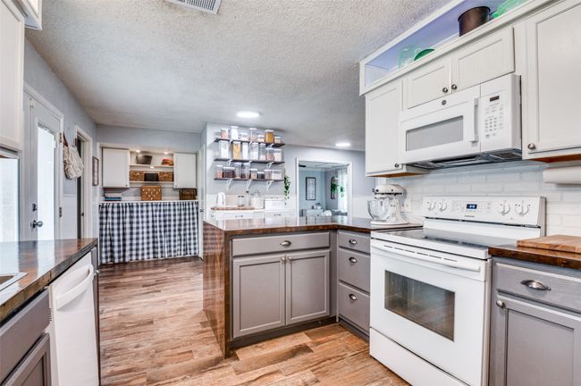 Kitchen featuring white appliances, gray cabinetry, a peninsula, light wood-style flooring, and a textured ceiling | Image 11