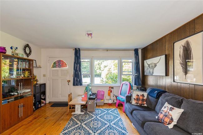 Living area featuring baseboard heating, wood walls, and light wood-style floors | Image 8