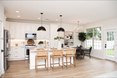 The kitchen has been remodeled and updated with new appliances, lighting, countertops, and the island has extra storage in it behind the bar stools | Image 1