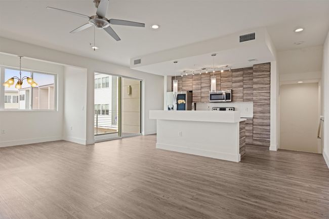 Unfurnished living room with track lighting, wood finished floors, a chandelier, ceiling fan, and recessed lighting | Image 5
