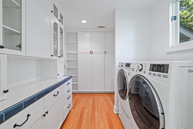 Laundry room featuring light wood-style floors, visible vents, recessed lighting, washing machine and clothes dryer, and cabinet space | Image 12