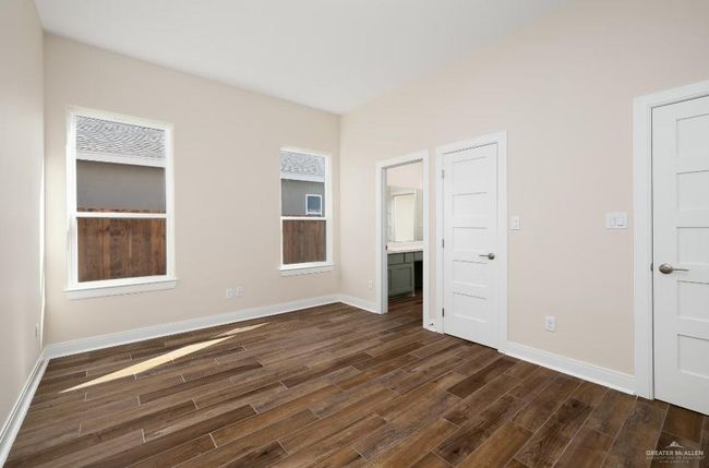 Unfurnished bedroom with dark wood-style floors, baseboards, and connected bathroom | Image 16