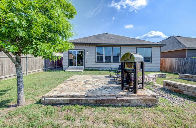 Rear view of house featuring roof with shingles, a fenced backyard, a fire pit, a patio area, and a lawn | Image 24