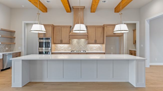Kitchen with pendant lighting, stainless steel appliances, open shelves, light wood-type flooring, and a spacious island | Image 16