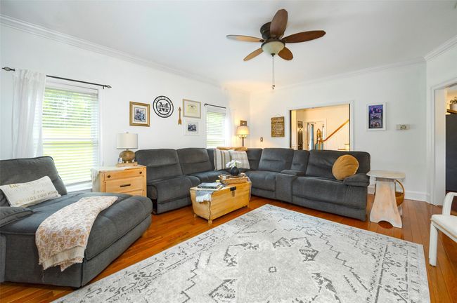 Living room with ornamental molding, hardwood / wood-style flooring, healthy amount of natural light, a ceiling fan, and stairway | Image 5