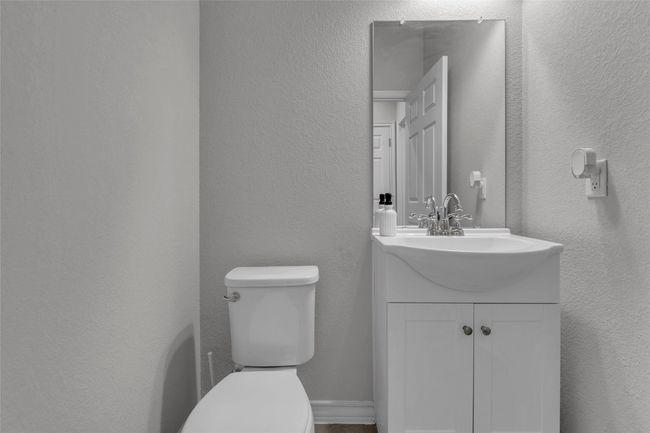 Half bathroom with toilet, vanity, and a textured wall | Image 25