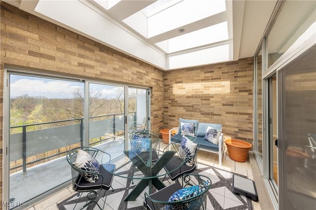 Sunroom featuring tile flooring, a skylight, outdoor dining area, sliders to balcony | Image 19