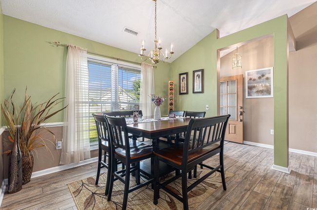 Dining space featuring a chandelier, wood finished floors, baseboards, and lofted ceiling | Image 10