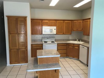 Kitchen with sink, light tile patterned floors, white appliances, a kitchen island, and backsplash | Image 3