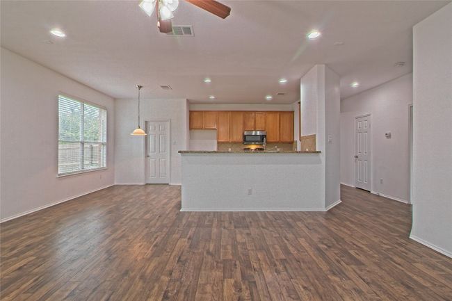 Unfurnished living room with dark wood-style floors, a ceiling fan, and recessed lighting | Image 6